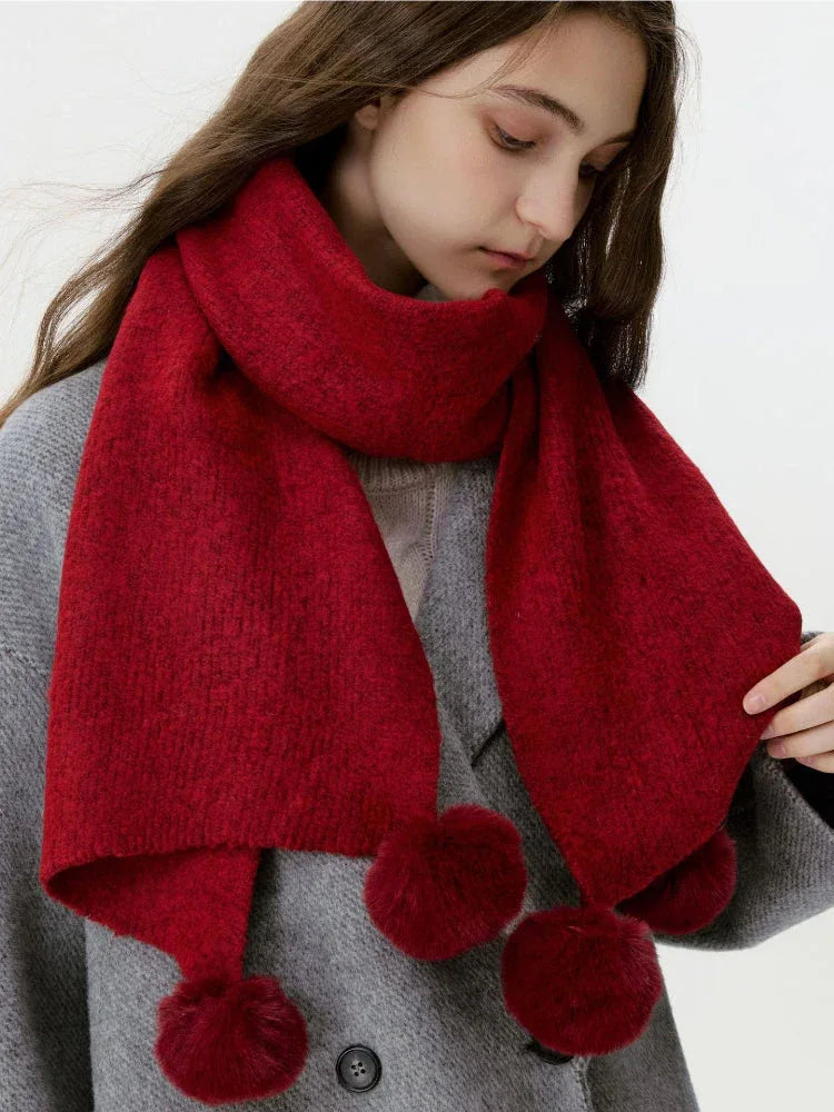 Woman wearing a red knit scarf with pom-pom embellishments