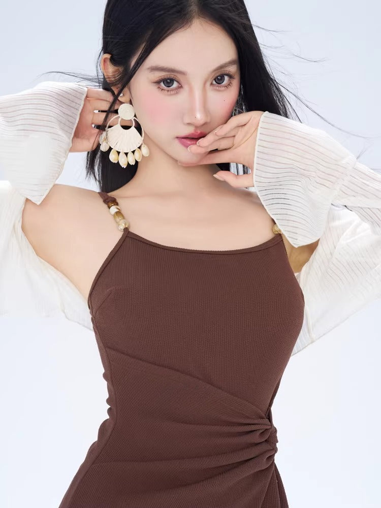 Close-up of a woman wearing a brown ruched mini dress and large white earrings.