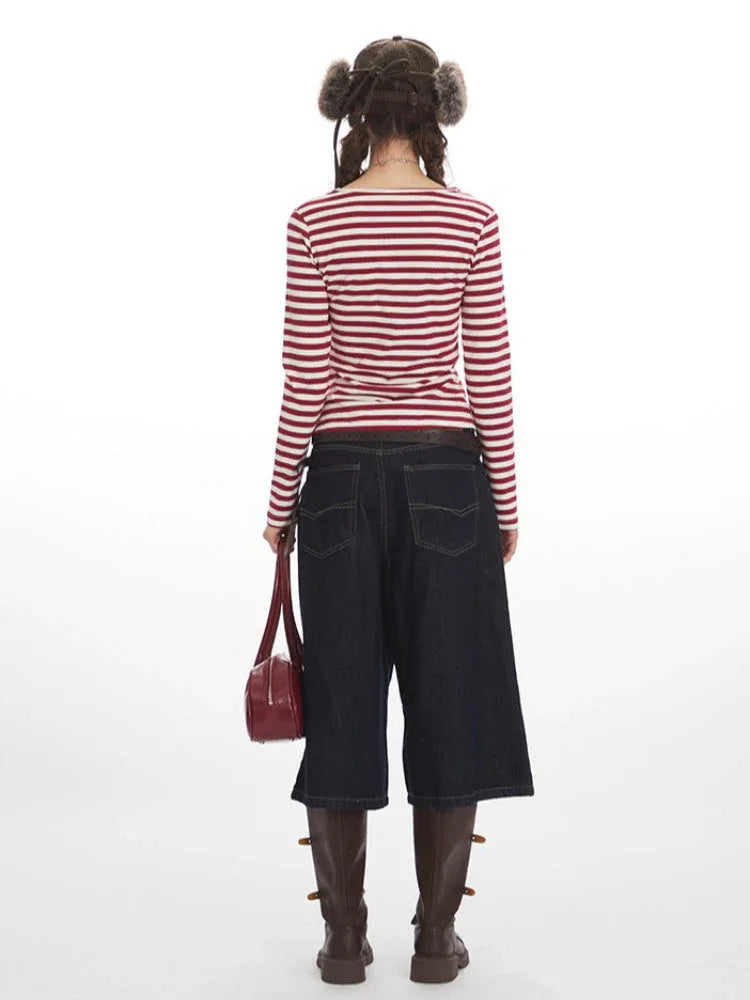 Rear view of a woman wearing a red and white striped long-sleeved shirt, dark wash wide-leg cropped jeans, and brown boots.