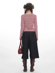 Rear view of a woman wearing a red and white striped long-sleeved shirt, dark wash wide-leg cropped jeans, and brown boots.