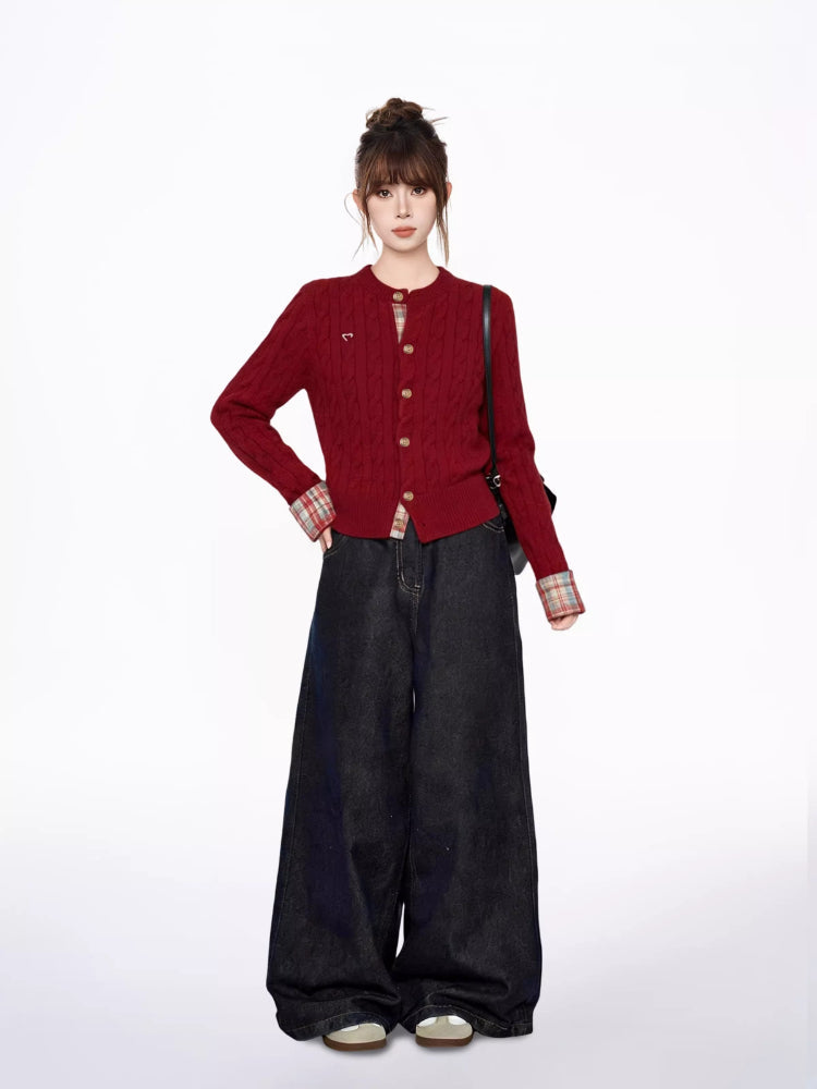 Full body shot of a woman in a red cable knit cardigan, plaid shirt, and wide-leg jeans, with hands on hips.