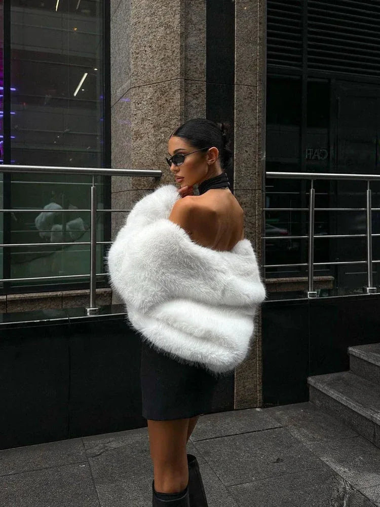 woman posing in a black dress and white faux fur jacket