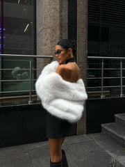 woman posing in a black dress and white faux fur jacket
