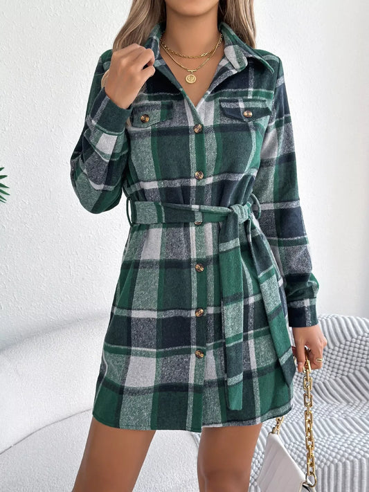 Close-up of a woman wearing a green plaid long-sleeve belted shirt dress