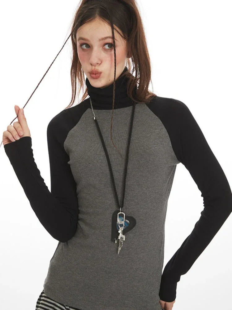 Close-up of model's face and upper body, showing the turtleneck and necklace.
