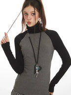 Close-up of model's face and upper body, showing the turtleneck and necklace.