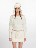 Close-up of a model wearing a white off-the-shoulder sweater with fuzzy trim and a matching mini skirt.