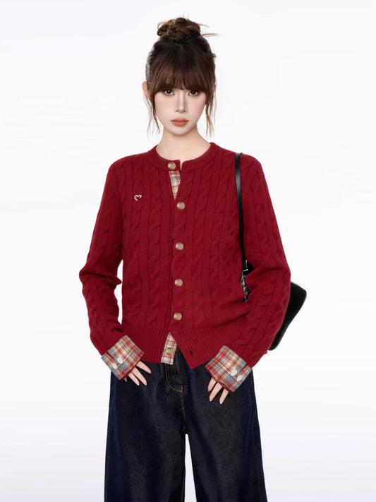 Close-up of the red cable knit cardigan, showing the button detail and embroidered heart.