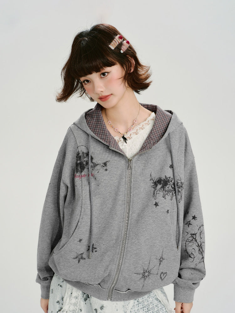 Close-up of a young woman wearing a grey zip-up hoodie with a graphic print, showing the details of the design.