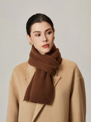 Close-up of a woman wearing a brown knit scarf and a tan coat.