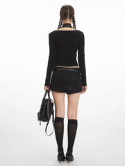 Back view of a woman wearing a black long-sleeve top and black mini skirt