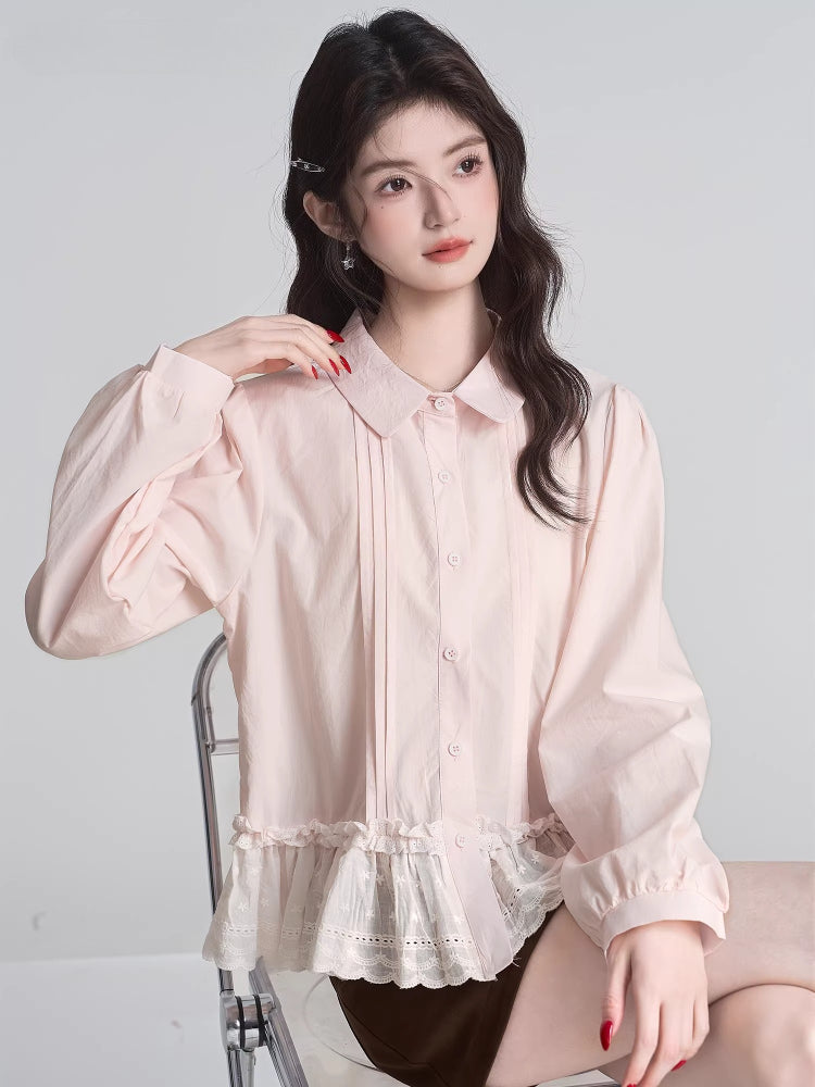 Woman sitting on a chair wearing a light pink ruffled peplum blouse with a Peter Pan collar and lace trim.