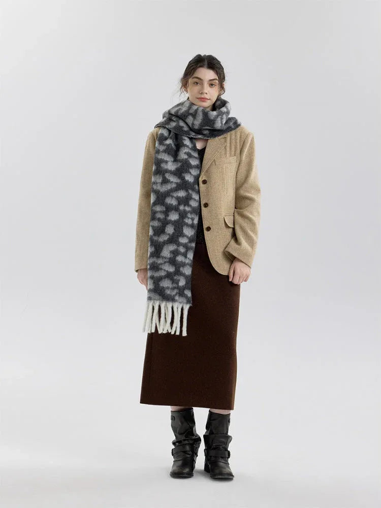 Woman wearing a tan blazer over a brown skirt and a grey and black leopard print scarf with white fringe