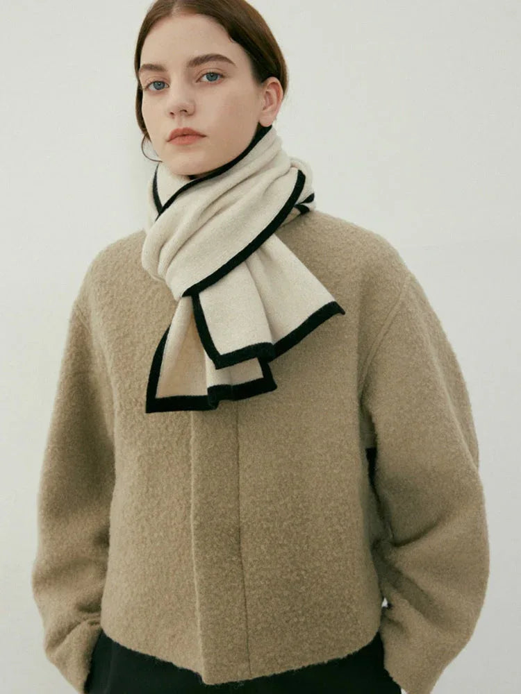 Woman wearing a beige textured coat and a cream scarf with black trim Main image