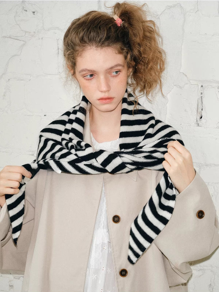 Model adjusting a black and white striped scarf around her neck