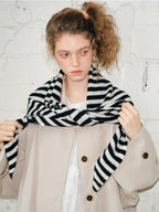 Model adjusting a black and white striped scarf around her neck