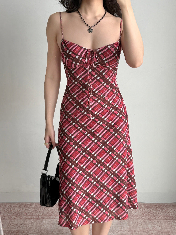 Full body shot of a woman in a red plaid midi dress, styled with a black necklace and handbag.