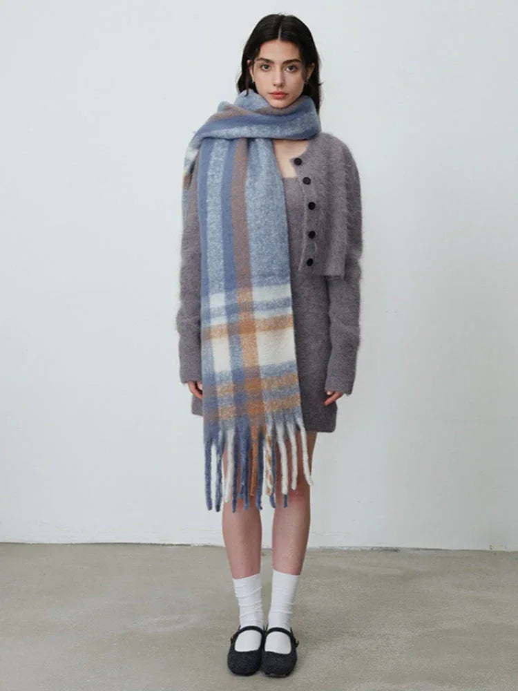 Woman in a grey knit dress, cardigan, and plaid scarf