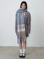Woman in a grey knit dress, cardigan, and plaid scarf