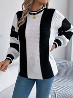 Woman wearing a black and white striped knit sweater and blue jeans, posing with her hand on her hip.