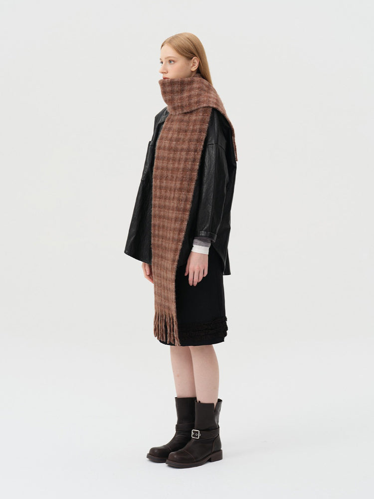 Woman in a brown plaid scarf, black leather jacket, and black skirt, viewed from the side.