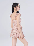 Rear view of a woman wearing a pink floral print mini dress with ruffle trim.