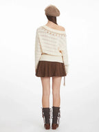 Back view of a woman wearing a cream-colored off-the-shoulder knit sweater with a brown A-line skirt.