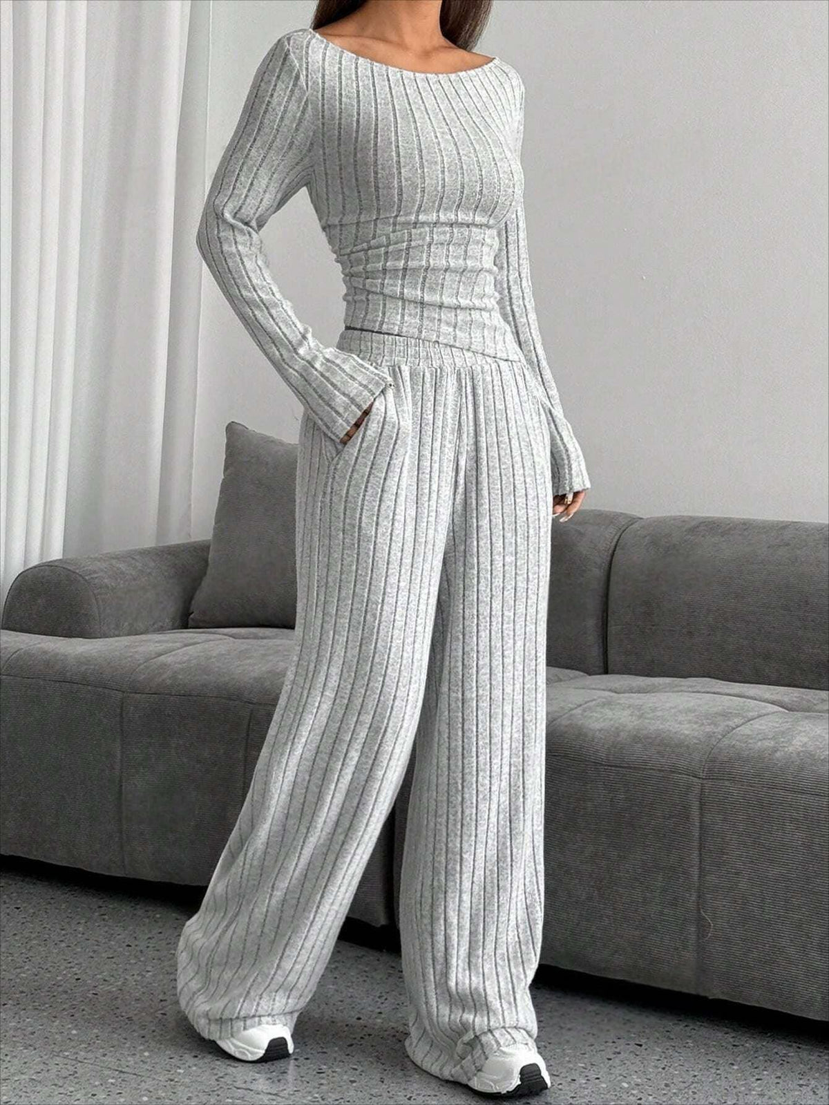 Model wearing a grey ribbed knit long sleeve top and wide leg pants set, standing indoors.