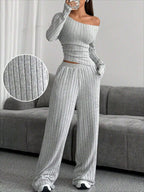 Close-up of the ribbed texture of the grey knit set worn by the model, standing indoors.
