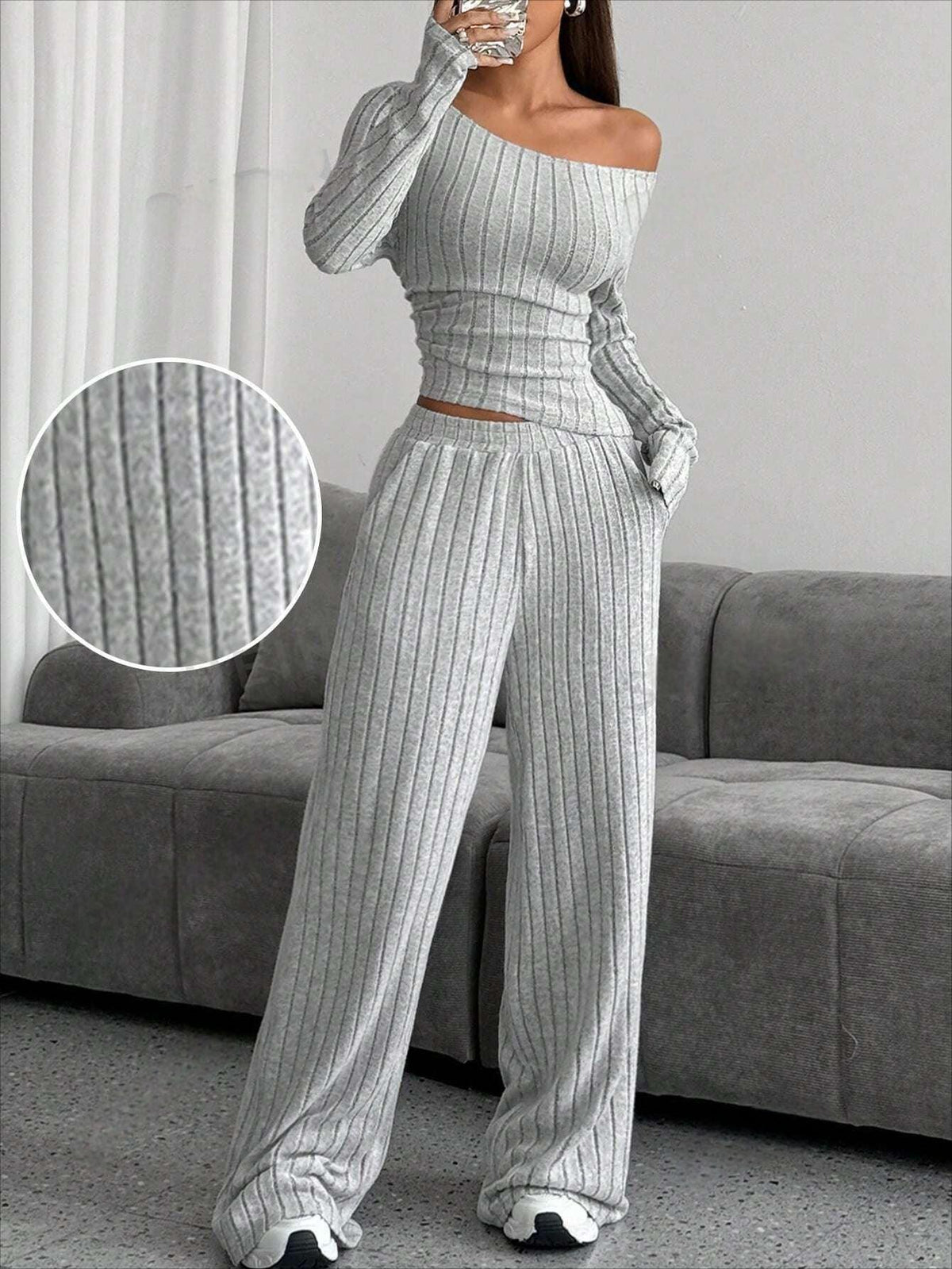 Close-up of the ribbed texture of the grey knit set worn by the model, standing indoors.