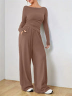 Woman wearing a brown long-sleeve top and wide-leg pants set, standing with hands in pockets.
