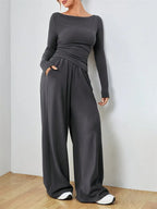 Woman wearing a charcoal gray long-sleeve top and wide-leg pants set, standing with hands in pockets.