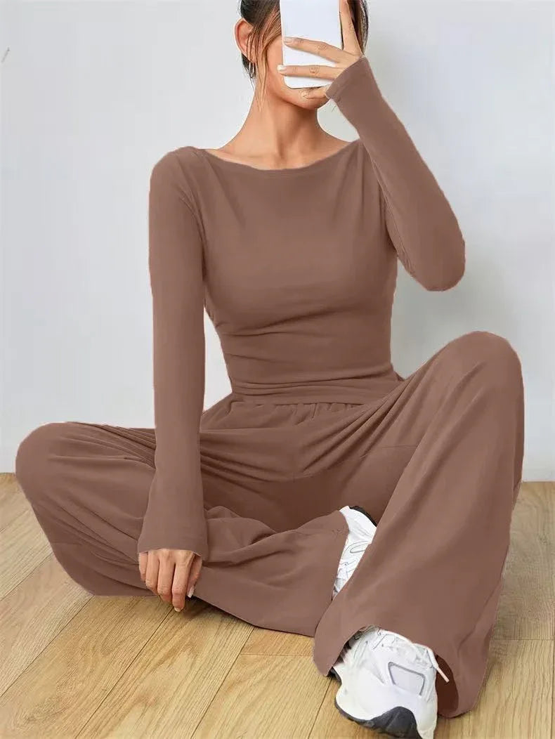 Woman wearing a brown long-sleeve top and wide-leg pants set, sitting on the floor and taking a selfie.