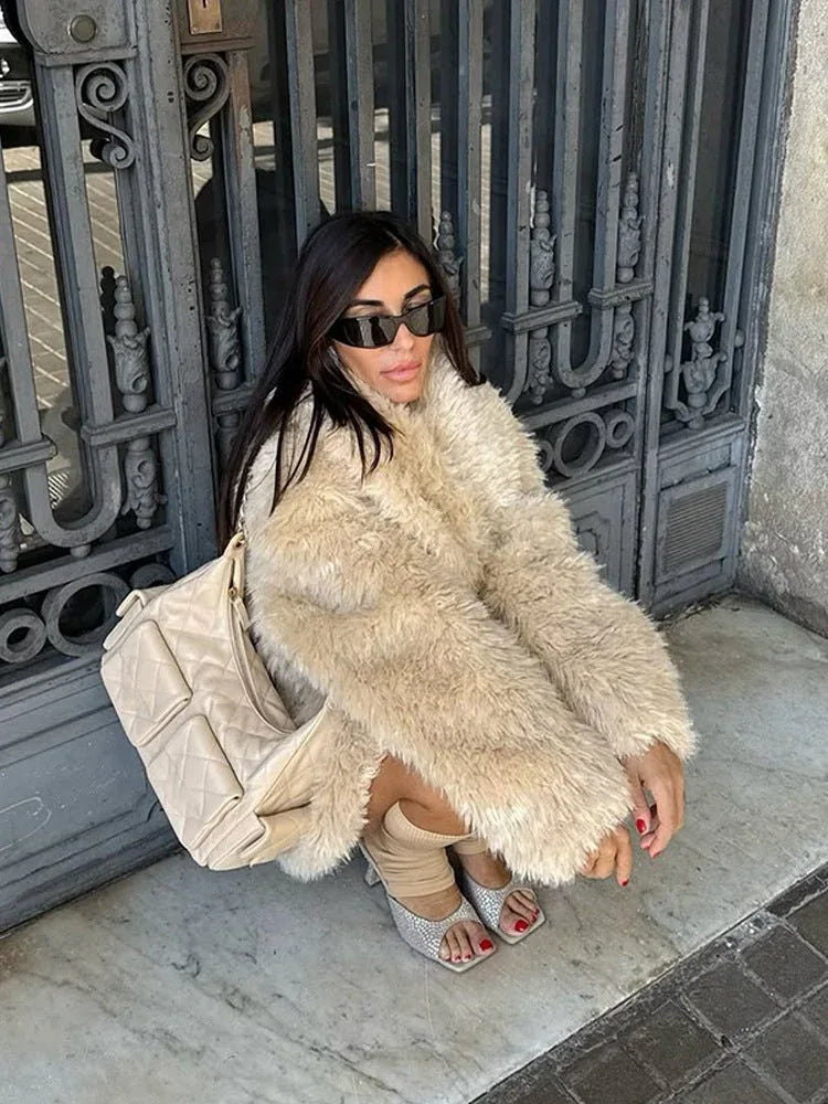 woman wearing a cream faux fur coat with a large collar and a belt, crouching down