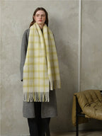 woman standing wearing a grey coat and a yellow plaid scarf