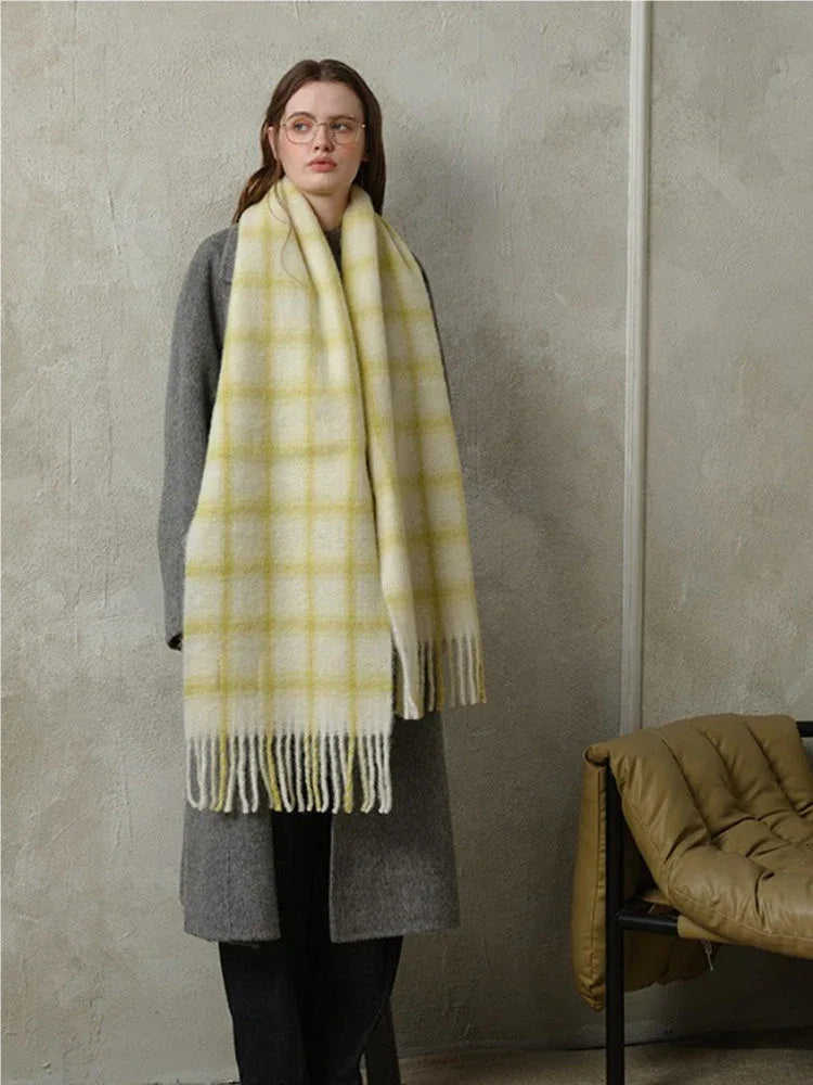 woman standing wearing a grey coat and a yellow plaid scarf