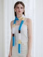 Model wearing a white ribbed tank top and off-white pants with a long, fluffy, color-blocked scarf hanging down.