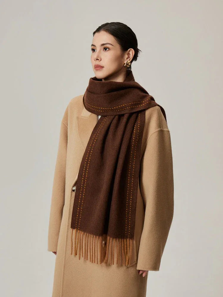 Woman wearing a brown scarf with orange detailing and a tan coat
