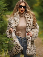 Woman wearing a spotted faux fur coat, blue jeans, and a beige turtleneck, adjusting her coat outdoors.