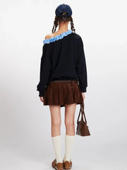 Back view of a model wearing a black off-the-shoulder sweatshirt with ruffled blue trim.
