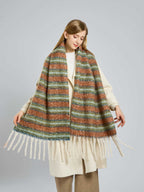 Woman with a cream coat and a colorful striped scarf draped around her shoulders