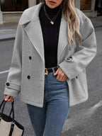 Front view of a woman in a grey peacoat, black turtleneck, and blue jeans.