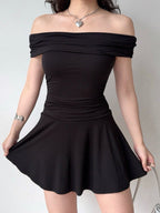Woman showing the flared skirt of a black off-the-shoulder knit dress.
