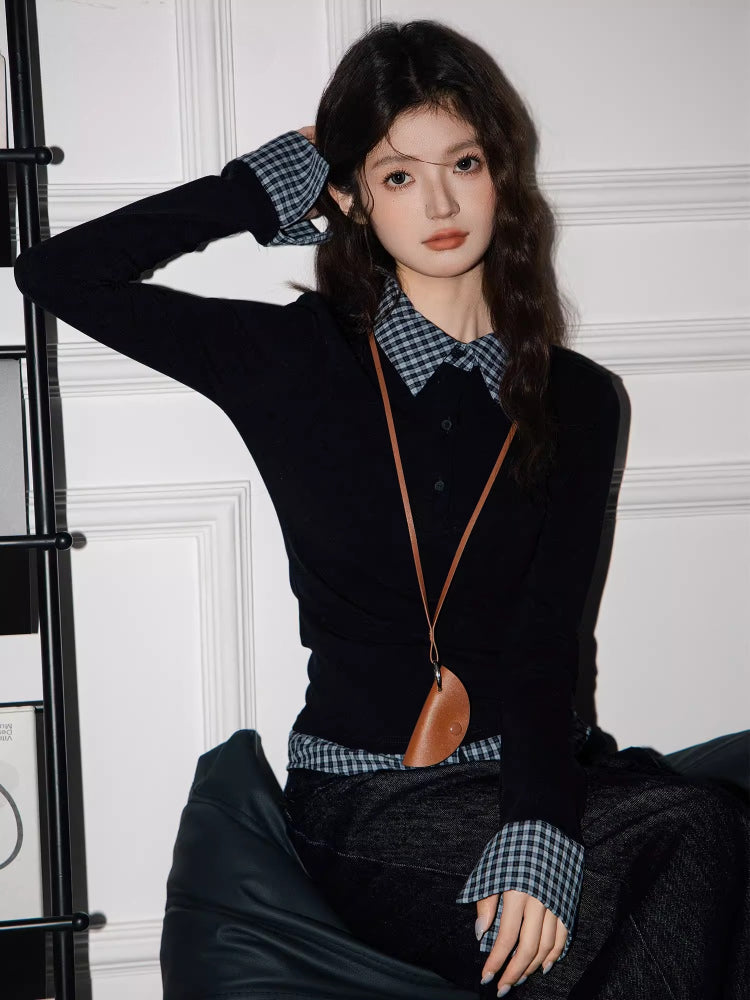 Model in a black long-sleeved top with checkered details, dark wash wide-leg jeans, and a brown bag, posing with one hand on her head.