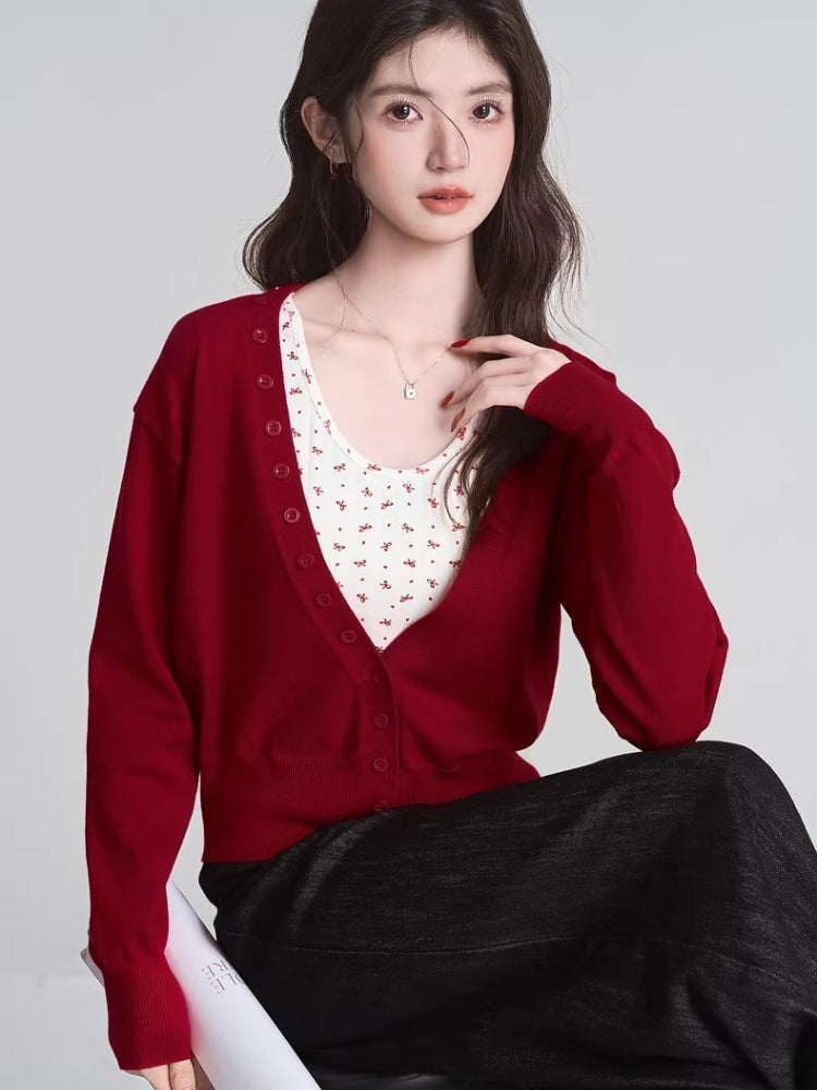Woman wearing a red V-neck cardigan and dark skirt, seated.