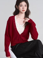 Woman wearing a red V-neck cardigan and dark skirt, seated.