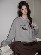 Close-up of a woman wearing a grey sweatshirt with a dachshund graphic and text "SUNLIGHT DAY" on the front.