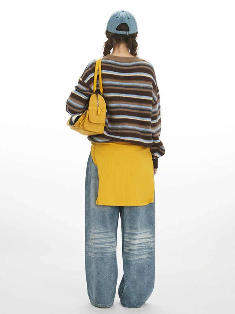 Model wearing a striped knit sweater, wide-leg jeans, and a yellow bag, back view.