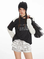 Close-up of the outfit, focusing on the layered shirt, ruffled shorts, and accessories, with the person winking.