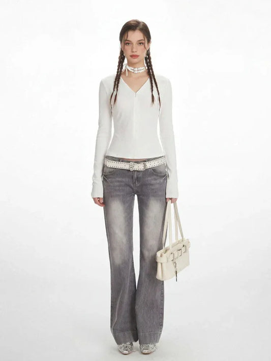 Model wearing a white long-sleeved ribbed V-neck top with grey flared jeans, a white studded belt, a white choker, and a white shoulder bag.